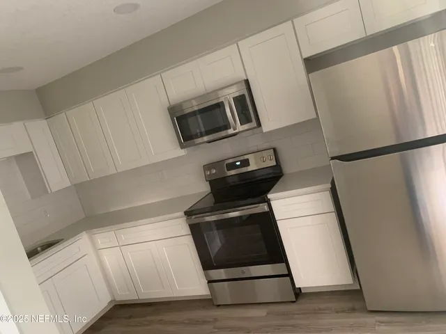 a kitchen with white cabinets and white appliances