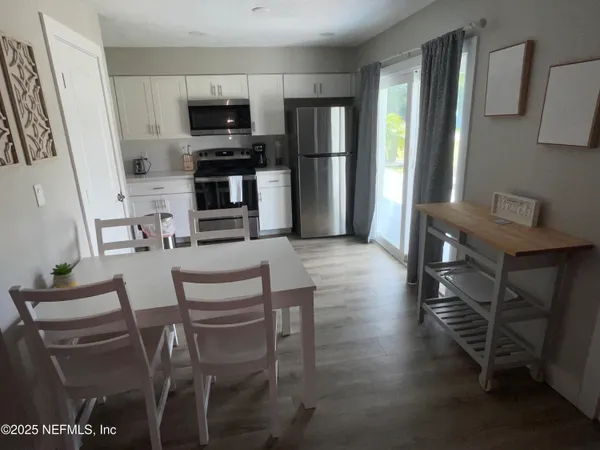 a kitchen with stainless steel appliances a stove a refrigerator and a dining table