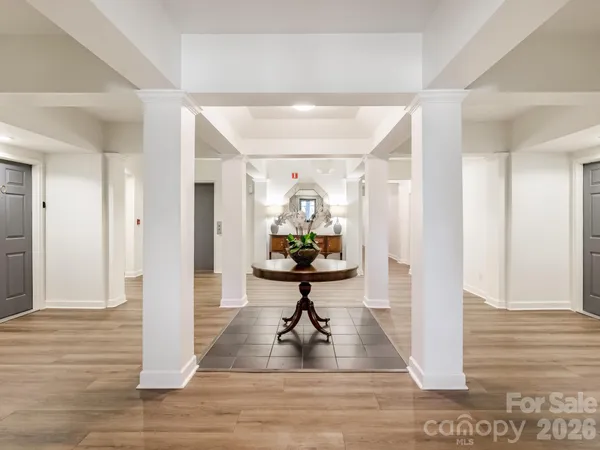 a view of a hallway with wooden floor table and chairs