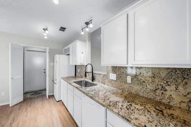 a kitchen with granite countertop a sink and cabinets
