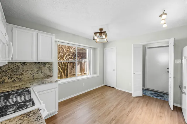 an empty room with wooden floor cabinet and windows