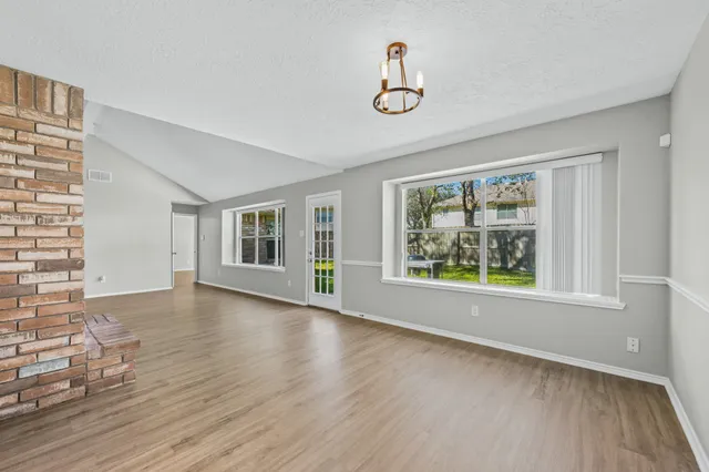 a view of an empty room with wooden floor and window