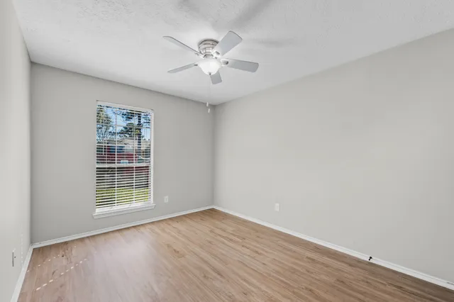 a view of an empty room with wooden floor and a window