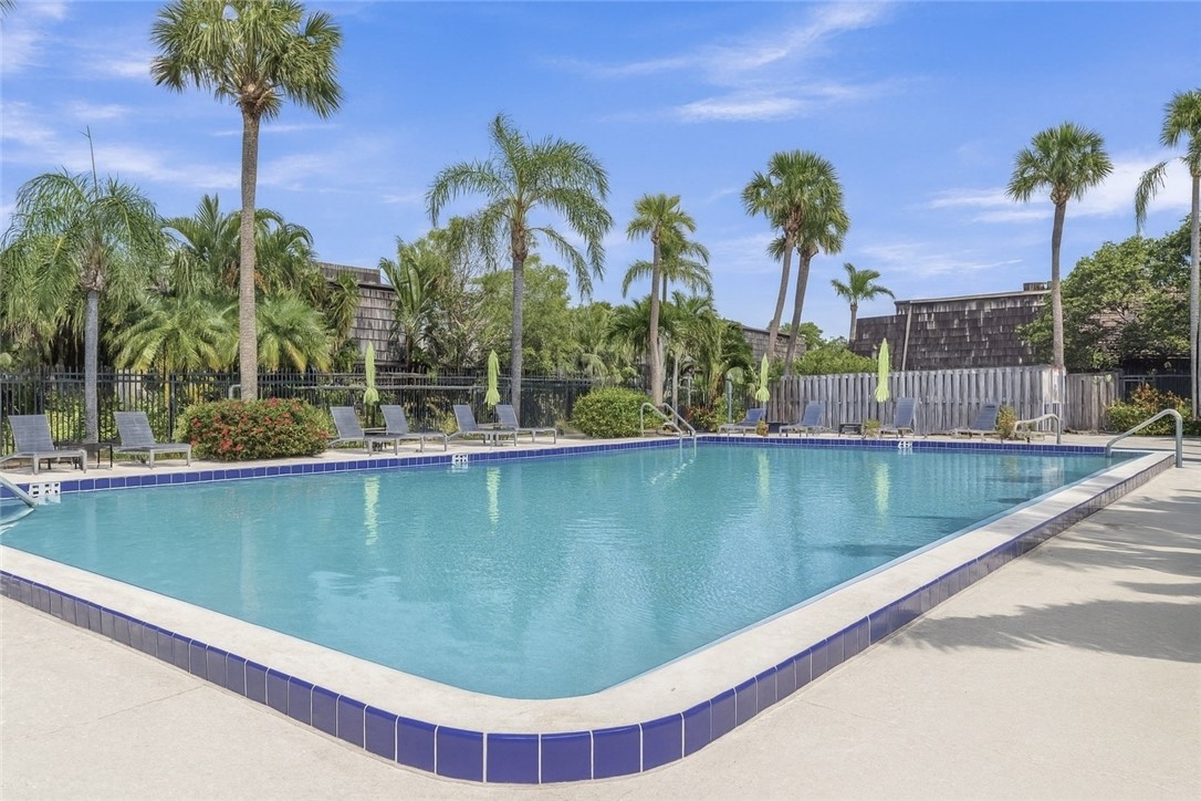465 East Waverly Place, Unit 8B Vero Beach, FL 32960 - Photo 26 of 28 a view of a swimming pool with a bench and palm trees
