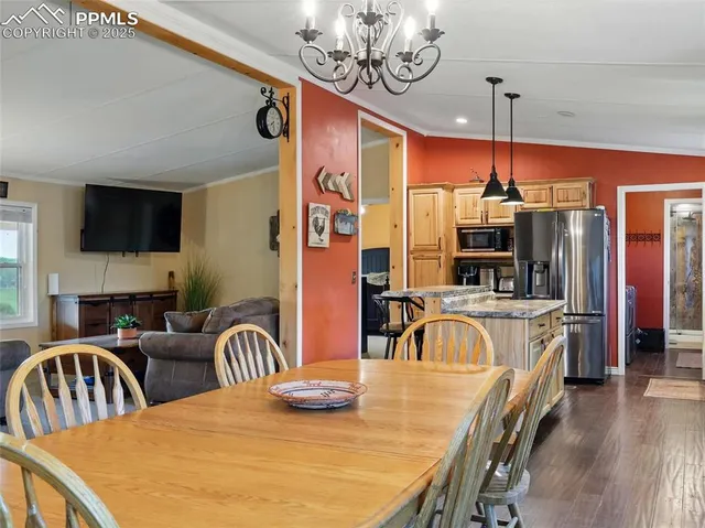 a kitchen with stainless steel appliances granite countertop a kitchen island a stove a dining table and chairs with wooden floor