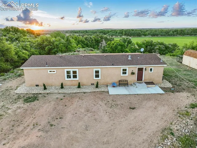 an aerial view of a house with a yard and trees in the background