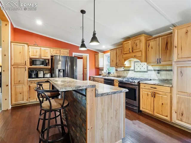 a kitchen with stainless steel appliances granite countertop a stove a sink dishwasher and a refrigerator with wooden floor