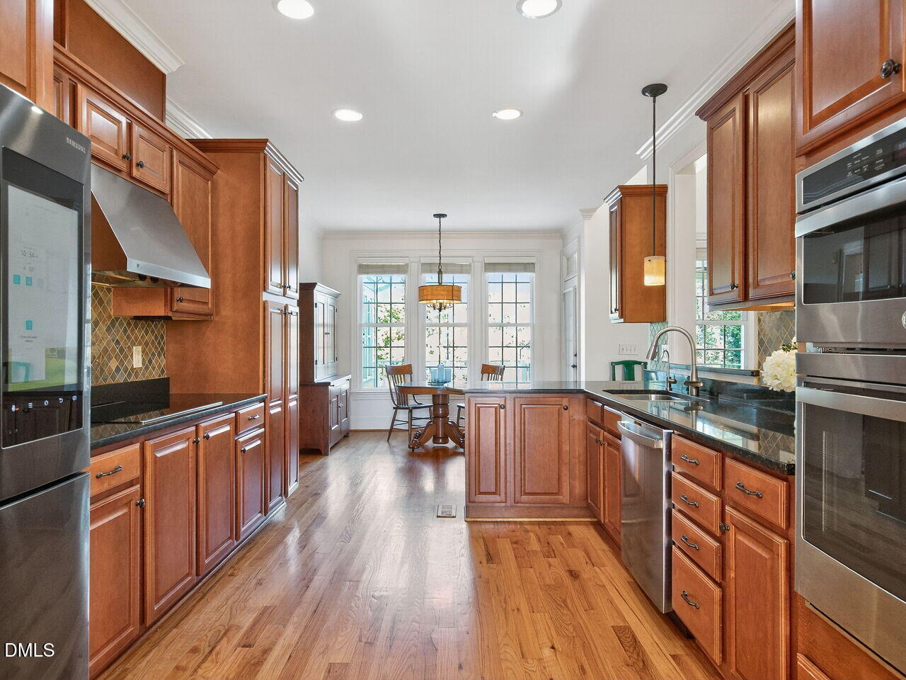 260 Marcellus Way Clayton, NC 27527 - Photo 8 of 47 a large kitchen with stainless steel appliances a large counter top a stove a chimney a sink and cabinets