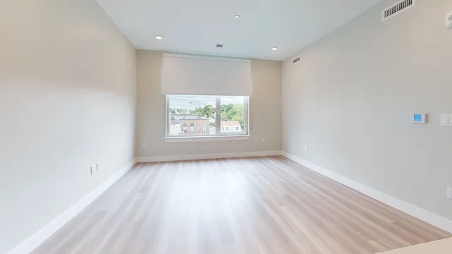 an empty room with wooden floor and windows