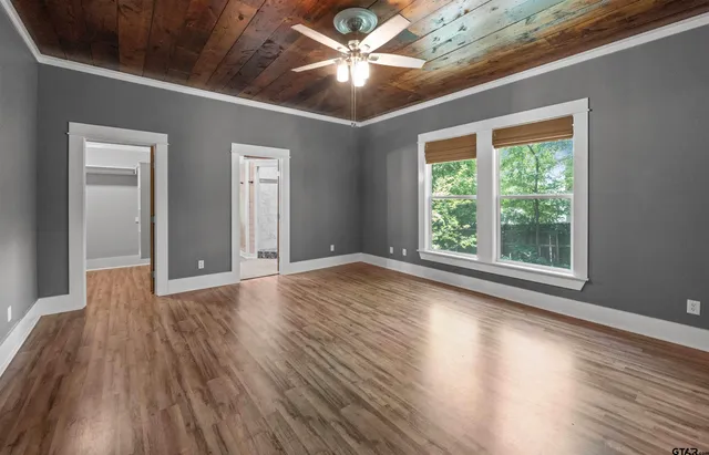 a view of an empty room with window and wooden floor