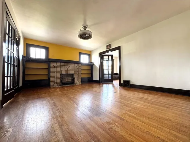 an empty room with windows and fireplace