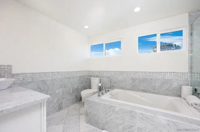a bathroom with a granite countertop bathtub sink and toilet