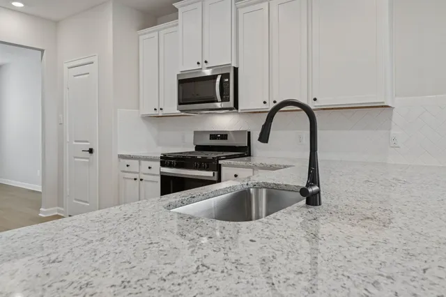 a kitchen with stainless steel appliances granite countertop a sink a stove and microwave