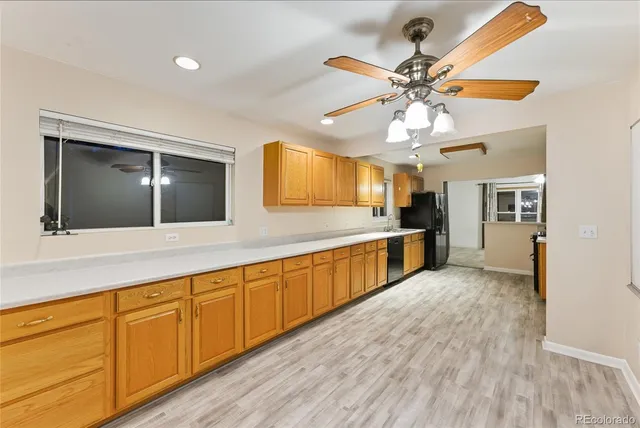 a large kitchen with stainless steel appliances a large counter top a sink and a chandelier
