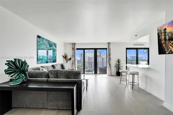 a living room with furniture and a dining table with kitchen appliances