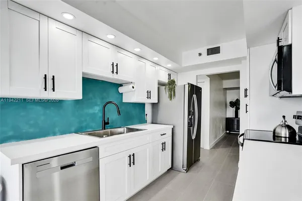 a view of a kitchen with white cabinets and wooden floor