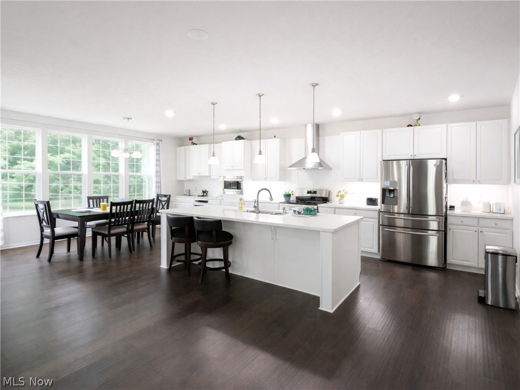4509 Millbrook Way Akron, OH 44321 - Photo 6 of 27 Open-concept kitchen featuring white cabinetry, stainless steel appliances, a large island with seating, recessed lighting, and dark wood-finish flooring
