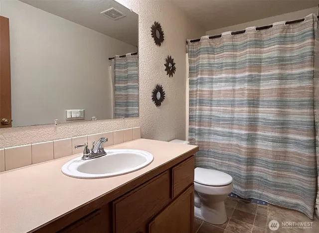 a bathroom with a sink a toilet and shower curtain