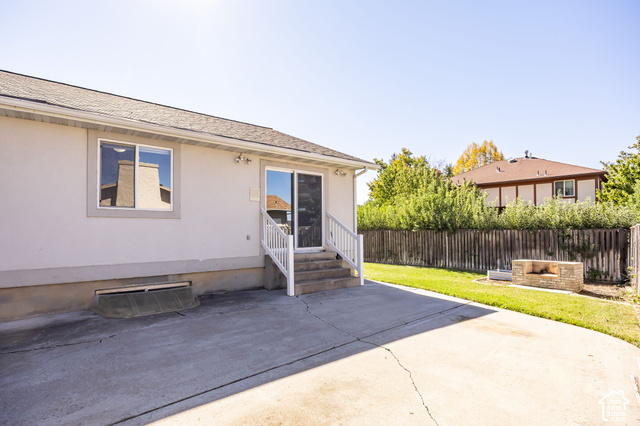 1143 East Mountain Road Logan, UT 84321 - Photo 42 of 64 Concrete patio with direct access to the backyard, featuring a built-in stone fire pit, a mature privacy fence, and a manicured lawn