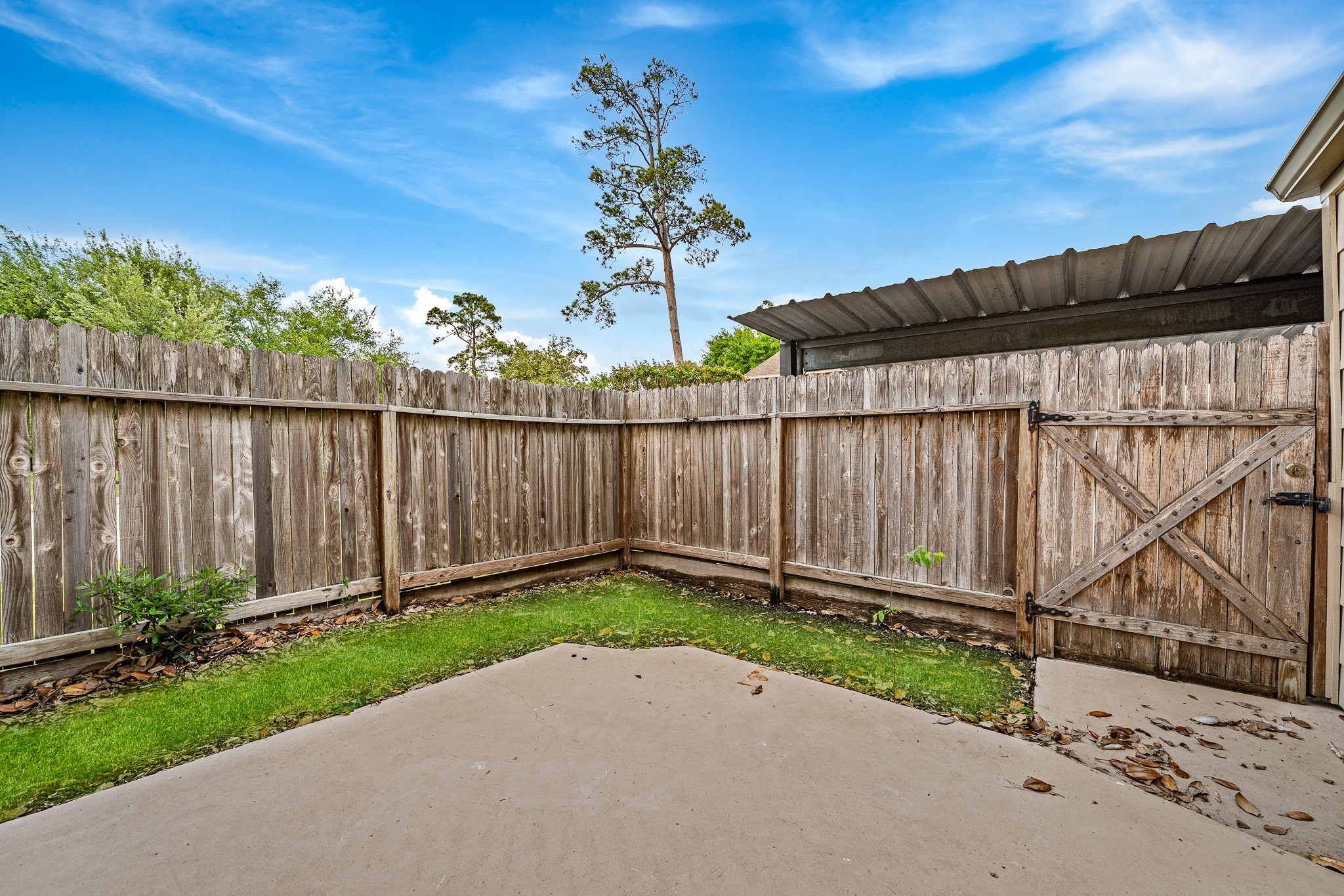 830 Threadneedle Street, Unit 240 Houston, TX 77079 - Photo 25 of 33 This photo shows a small, fenced backyard with a concrete patio and a patch of grass. The wooden fence provides privacy, and there's a covered area on one side, ideal for outdoor activities or storage.