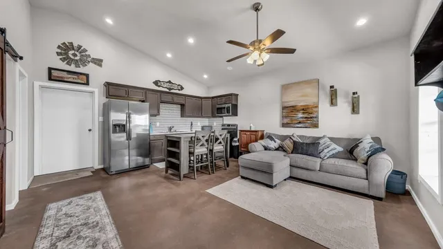a living room with furniture kitchen view and a window