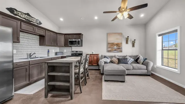 a living room with stainless steel appliances kitchen island granite countertop furniture and a fireplace