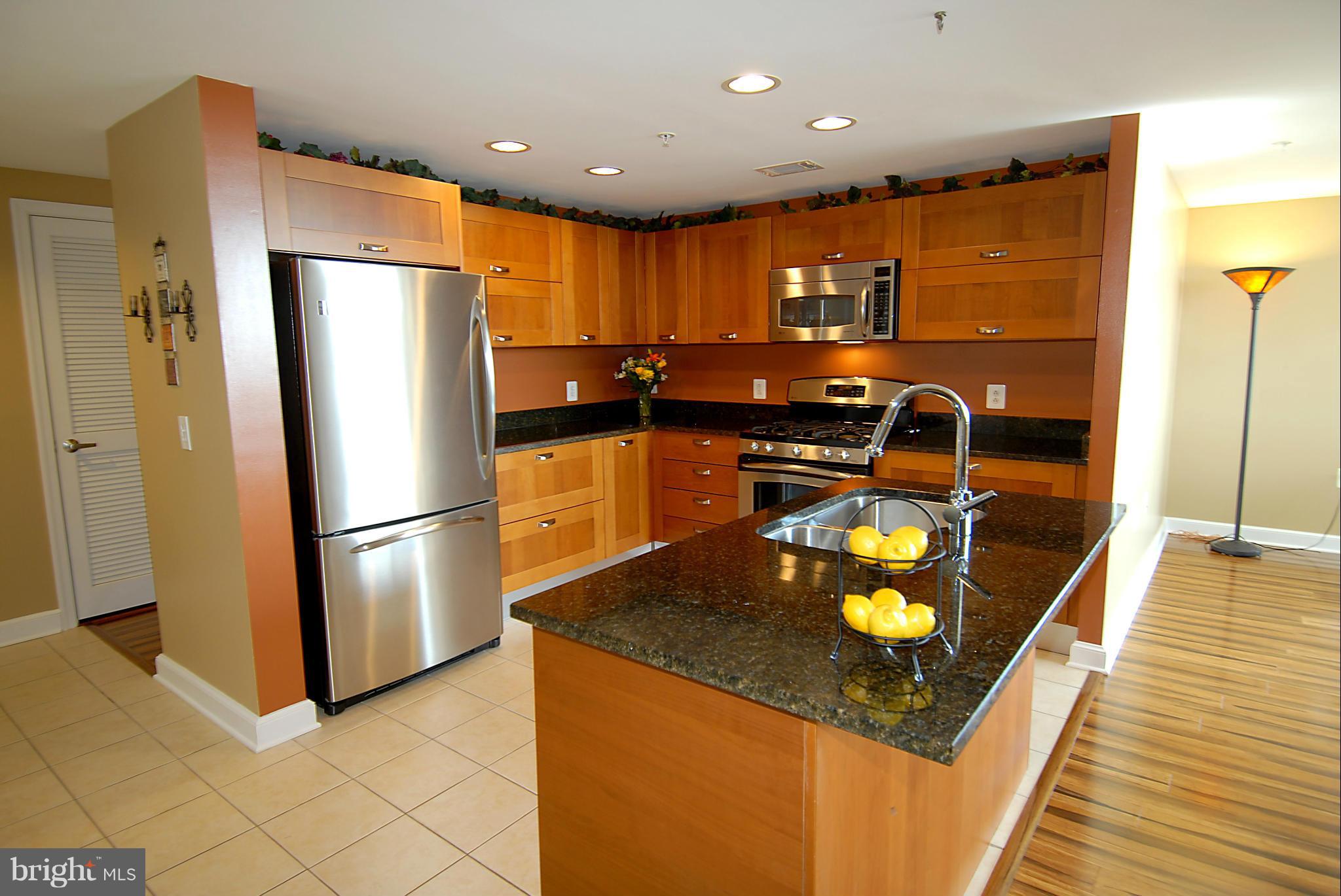 a kitchen with stainless steel appliances granite countertop a refrigerator a stove and a sink with granite countertops