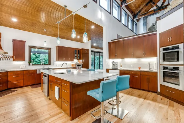 a kitchen with stainless steel appliances kitchen island granite countertop a table chairs and a sink