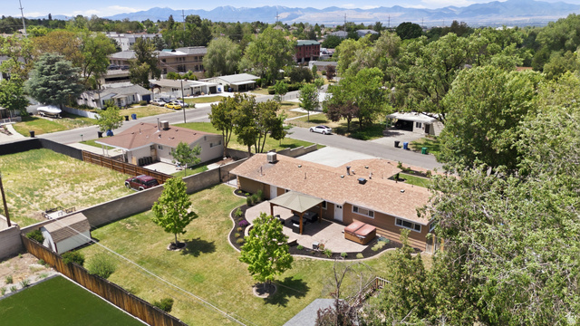 6889 South Village Road Salt Lake City, UT 84121 - Photo 43 of 44 Expansive backyard featuring a manicured lawn, established trees, and a concrete patio with a covered outdoor area