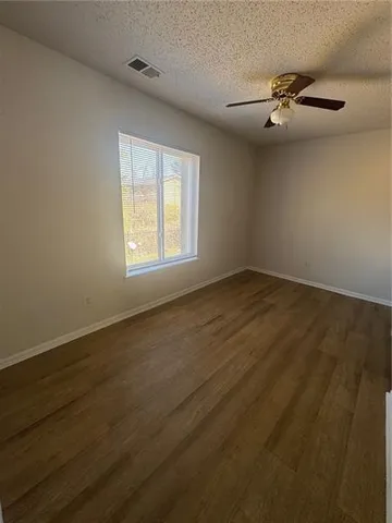 an empty room with wooden floor fan and windows