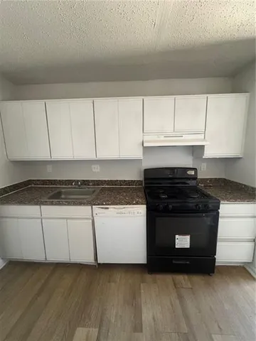 a kitchen with granite countertop a stove and a white cabinets