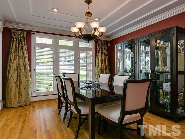 7905 Ogden Court Raleigh, NC 27613 - Photo 14 of 25 a dining room with wooden floor a chandelier a glass table and chairs