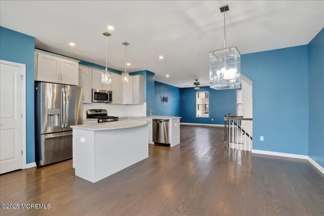 an empty room with wooden floor chandelier and windows