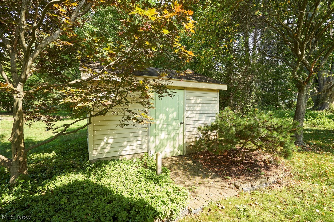 299 West Caston Road New Franklin, OH 44319 - Photo 21 of 23 Garden shed featuring horizontal vinyl siding, a light green door, and a dark shingle roof