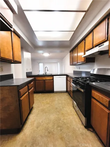 a large kitchen with stainless steel appliances granite countertop a stove a sink dishwasher and a refrigerator