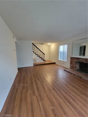 a view of an empty room with wooden floor and a fireplace