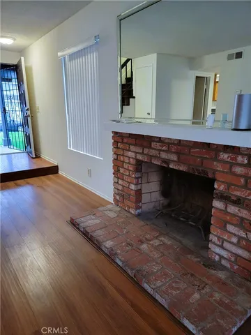 a living room with a fireplace wooden floor and potted plant