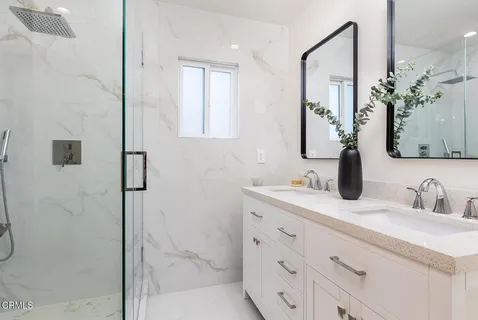 a bathroom with a double vanity sink mirror and shower