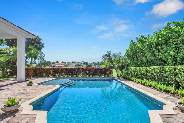 a view of a house with pool plants and a lawn chairs under an umbrella