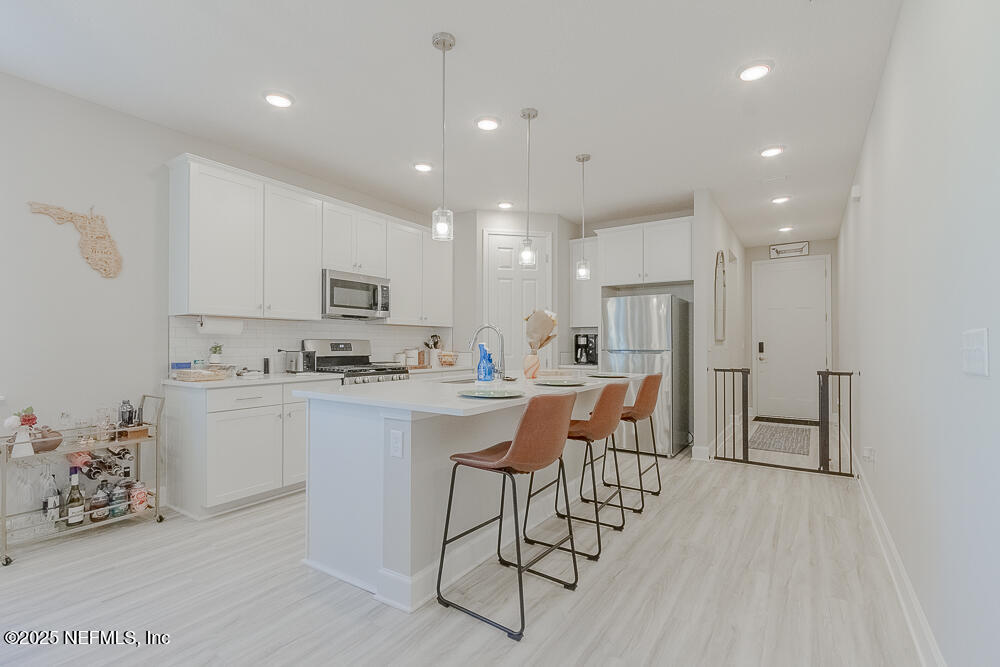 3616 Cunningham Road Orange Park, FL 32065 - Photo 8 of 48 a kitchen with stainless steel appliances kitchen island granite countertop a refrigerator a stove a sink dishwasher and a dining table with wooden floor