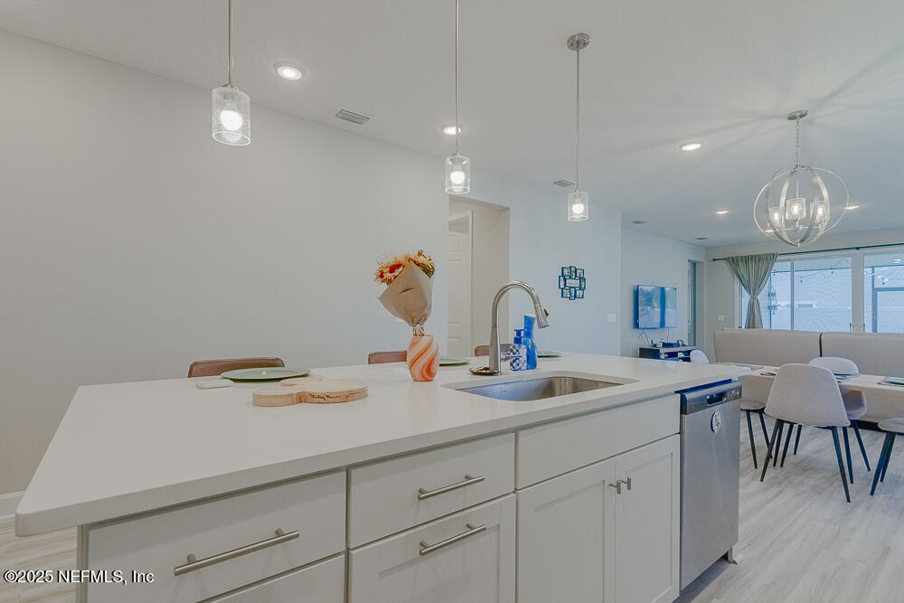 3616 Cunningham Road Orange Park, FL 32065 - Photo 10 of 48 a kitchen with a sink dishwasher a dining table and chairs with wooden floor