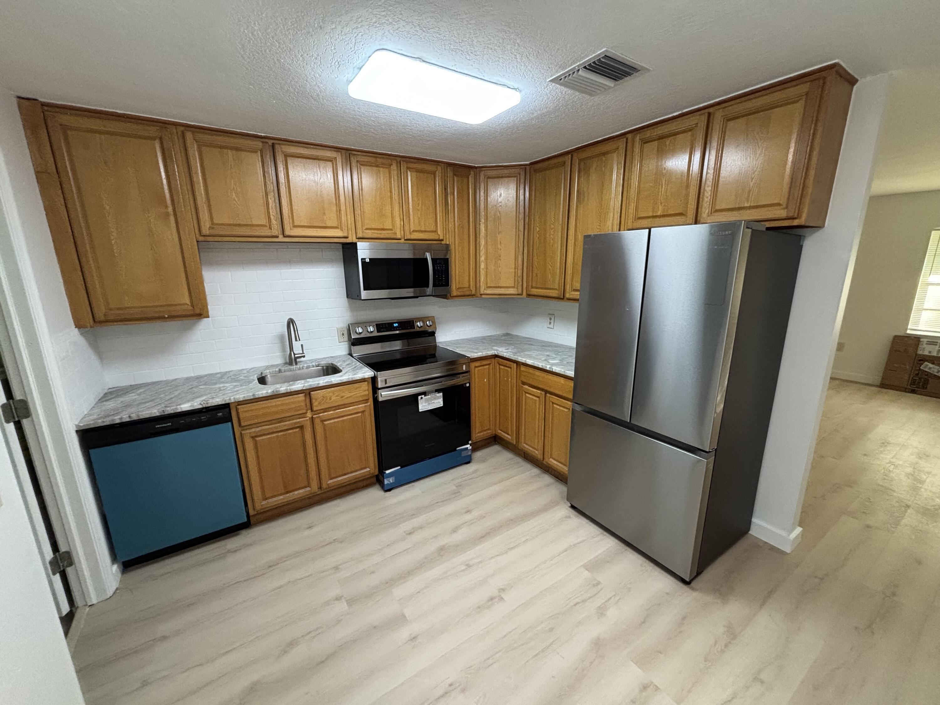 a kitchen with stainless steel appliances granite countertop a refrigerator stove a sink dishwasher and microwave