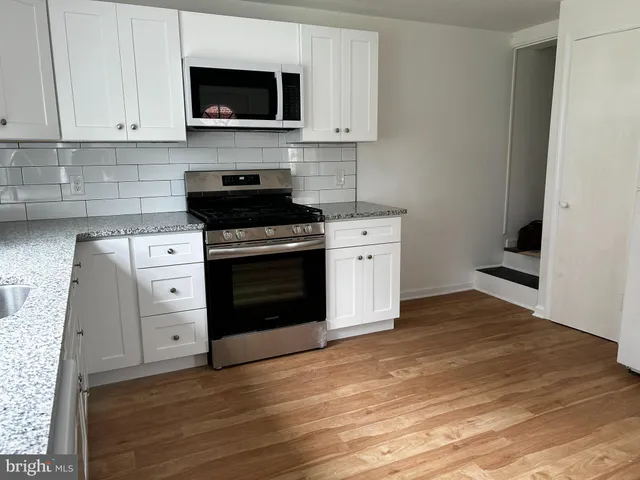 a kitchen with stainless steel appliances white cabinets and a stove top oven