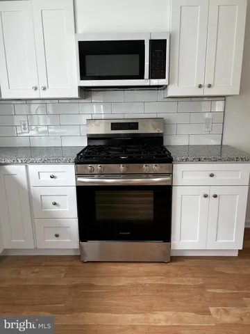 a kitchen with granite countertop a stove and a microwave