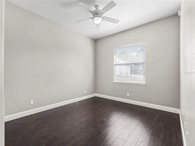 an empty room with wooden floor closet and windows