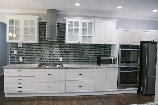 a kitchen with granite countertop a refrigerator and cabinets