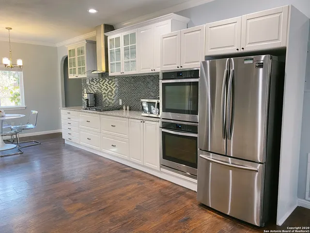 a kitchen with granite countertop stainless steel appliances a refrigerator and wooden floor