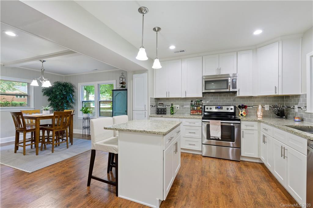 5600 Seacroft Road Charlotte, NC 28210 - Photo 8 of 18 a kitchen with kitchen island granite countertop a stove a sink a dining table and chairs with wooden floor