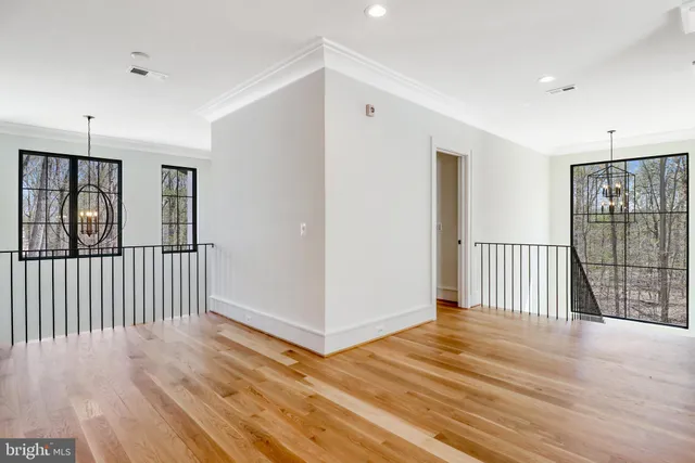 an empty room with wooden floor ceiling fan and windows