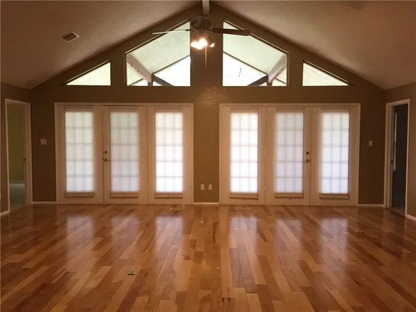 a view of an empty room with a large window and wooden floor